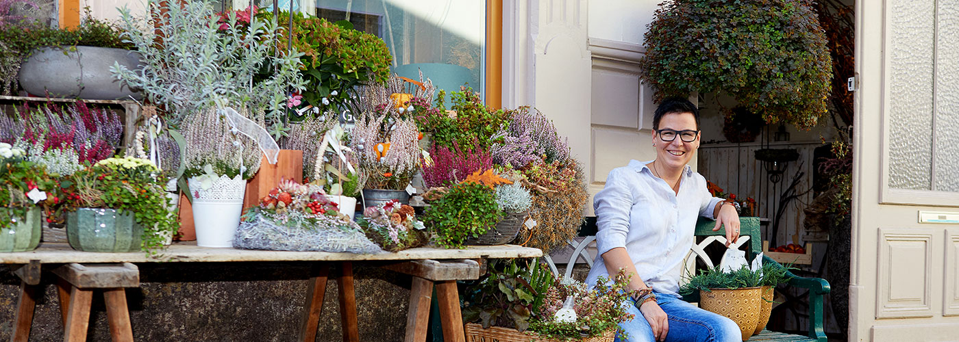 Kathrin Kremser auf der Bank sitzend-vor ihrem Laden