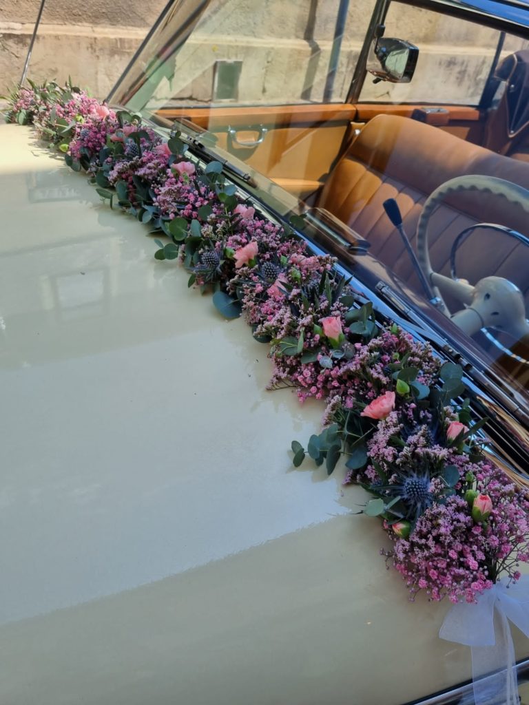weißer Mercedes Oldtimer mit Blumengirlande Hochzeitsschmuck